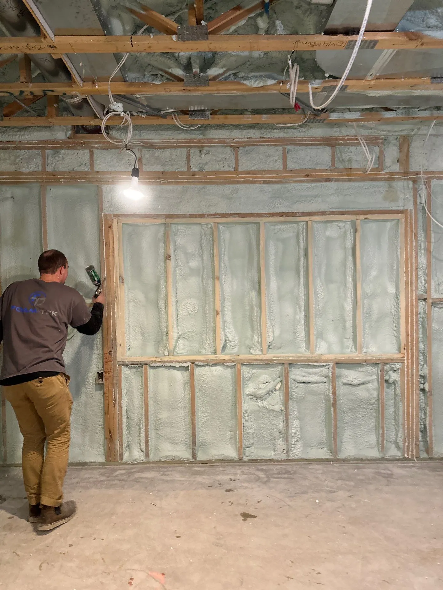Foam-Tek technician trimming cured spray foam flush with the wall framing